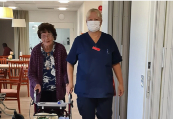 En medarbetare iförd munskydd hjälper en boende