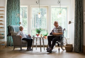 Två äldre personer fikar framöver ett stort fönster