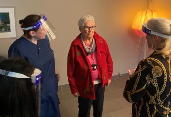 En boende möter två medarbetare som bär genomskinliga visir