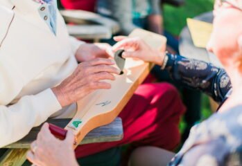 Två äldre personer spelar på ett litet stränginstrument