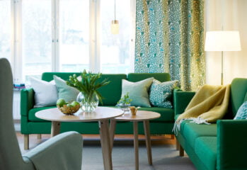 En grön soffgrupp med ljusa kuddar, träfärgat vardagsrumsbord.