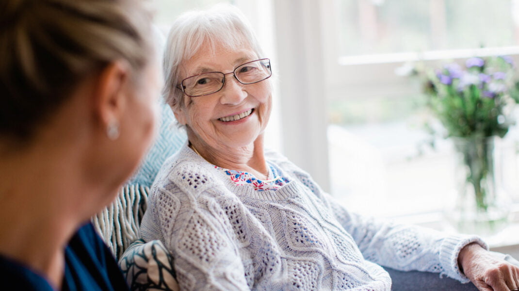 En omsorgstagare ler mot en medarbetare
