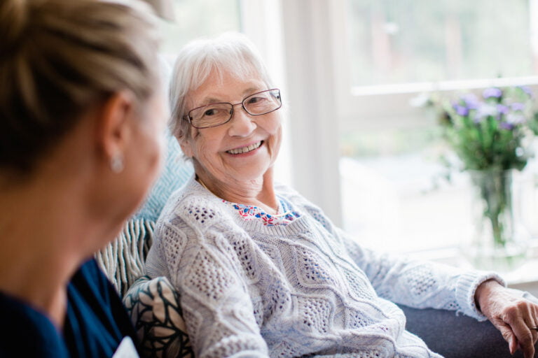 En omsorgstagare ler mot en medarbetare