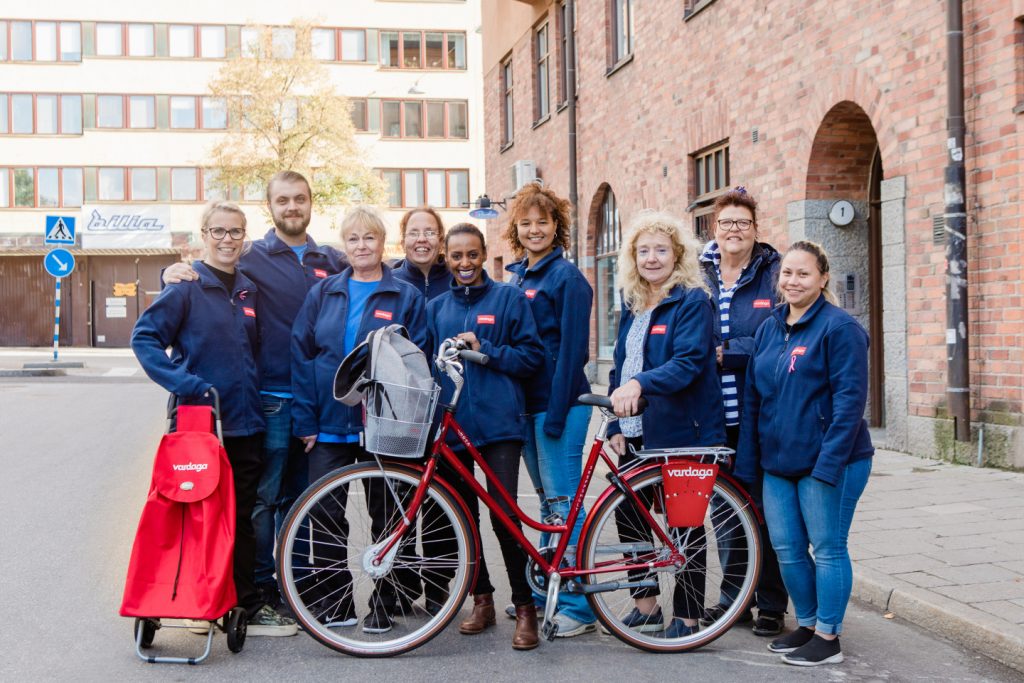 gruppbild på hemtjänstpersonal i blå kläder cykel längst fram