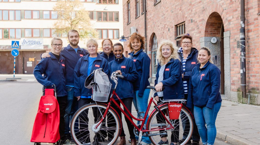 gruppbild på hemtjänstpersonal i blå kläder cykel längst fram
