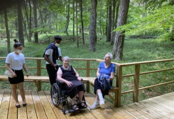 Boende och personal på ett trädäck i skogen