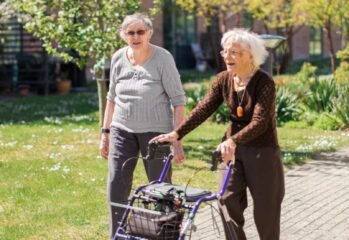 Två personer promenerar i en grönskande trädgård