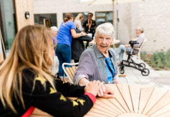En omsorgstagare håller handen om en medarbetares hand medan de pratar
