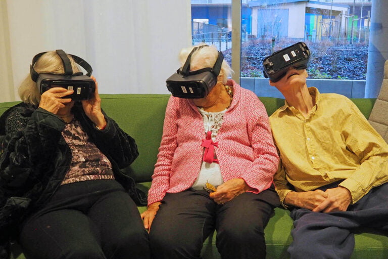 Tre boenden sitter i en soffa och provar VR-glasögon