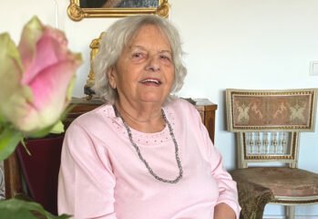 Porträtt på Marianne i rosa tröja sittande i sitt hem.