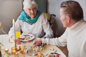 äldre kvinna och man sitter tillsammans vid dukat matbord