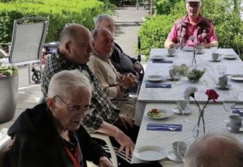 Boende sitter vid ett dukat långbord utomhus