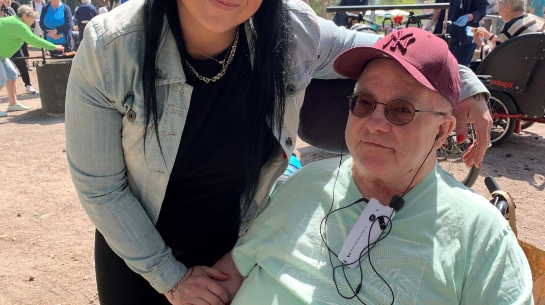 Kvinna och äldre man i rullstol med solglasögon i lekpark
