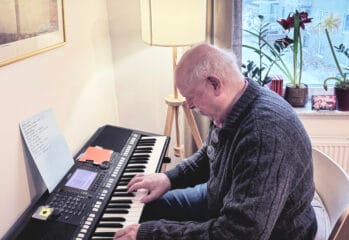 Lars, boende på Vardaga Villa Bromsten, spelar på synt bredvid fönstret