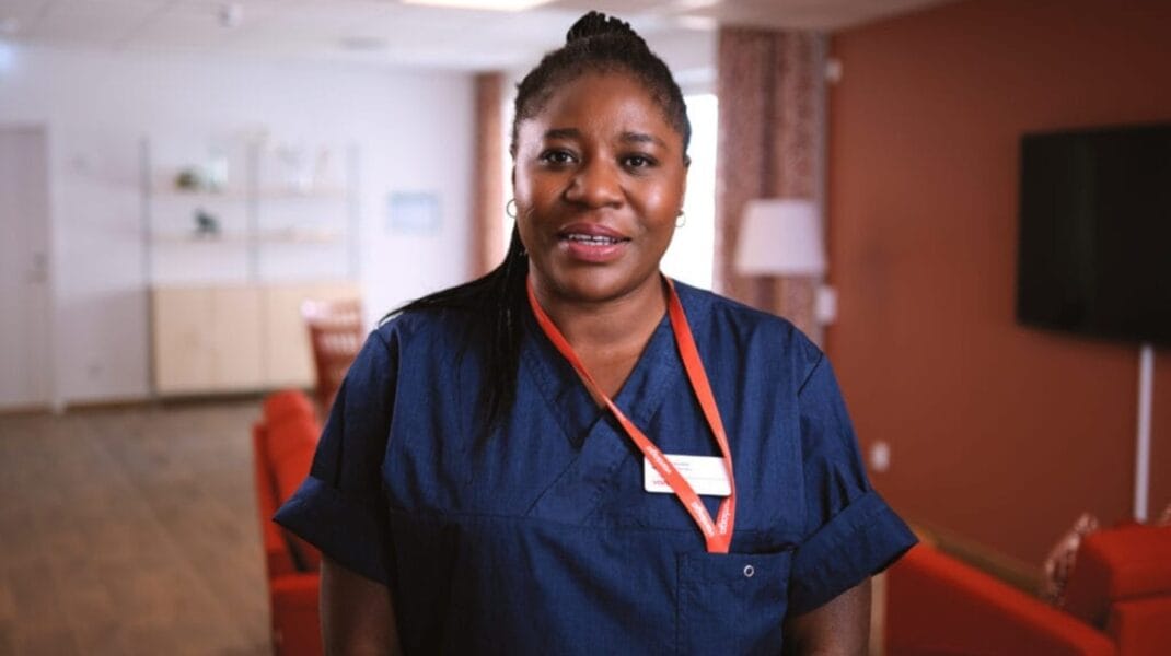 Porträttbild på sjuksköterskan Inoussa Barikissou i blå mörkblå uniform och rött nyckelband