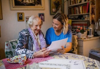 Äldre kvinna tittar på papper tillsammans med en personal