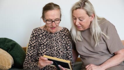 Äldre kvinna och yngre kvinna tittar på ett fotografi tillsammans
