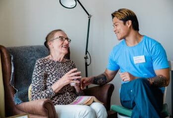 Äldre kvinna och personal samtalar och ler mot varandra