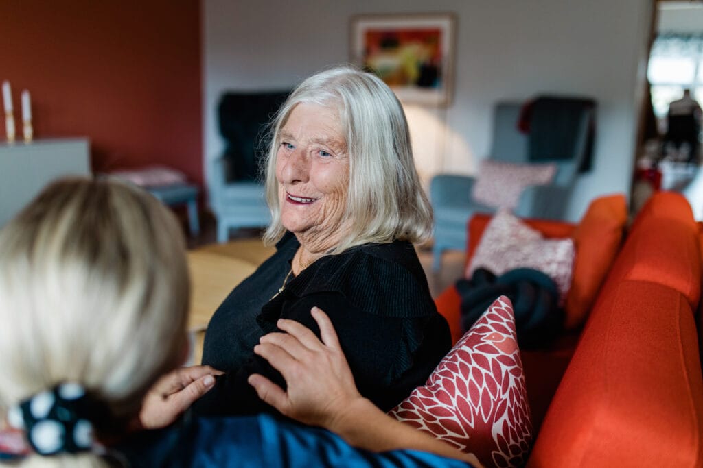 Äldre kvinna ler och samtalar med en yngre kvinna