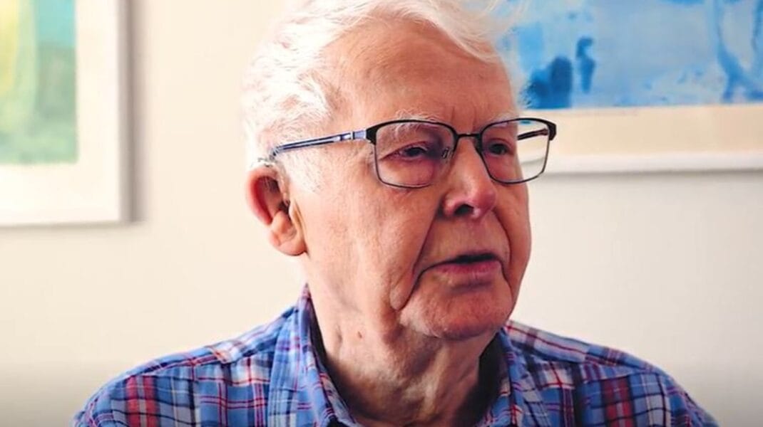 Porträttbild på Anders kort vitt hår, rutig skjorta och glasögon med svart båge