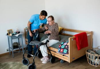 personal hjälper en boende upp från sängkanten