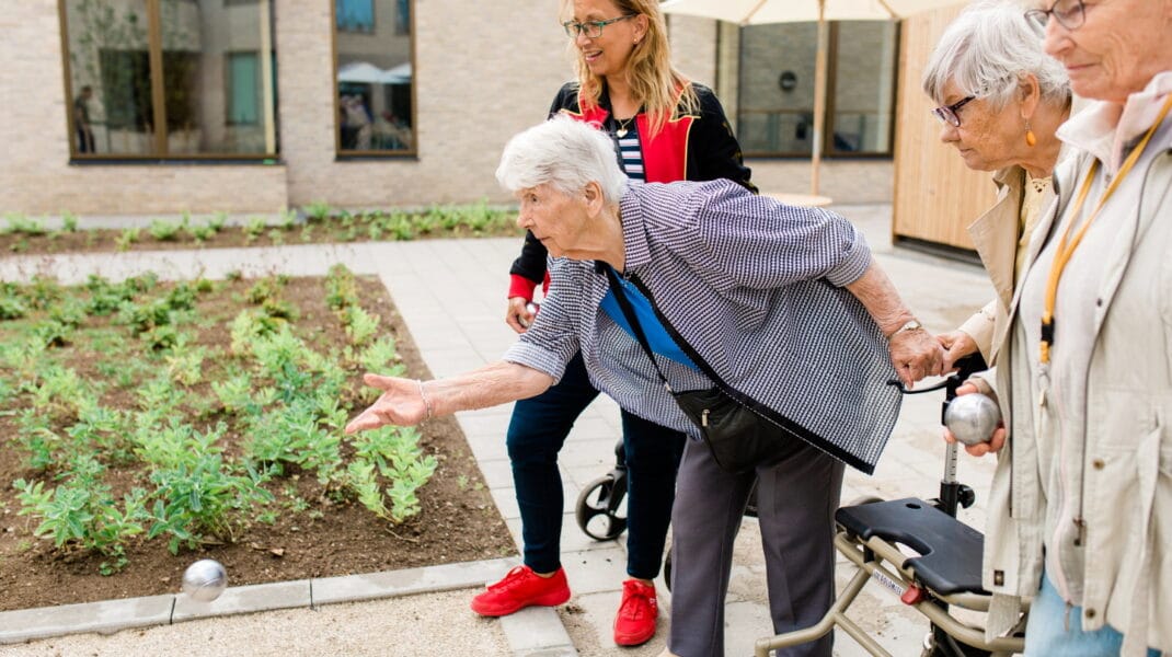 tre kvinnor spelar boule tillsammans på äldreboendet