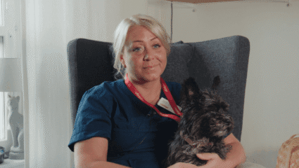 Porträtt Jennifer pettersson med hunden Rambo knät